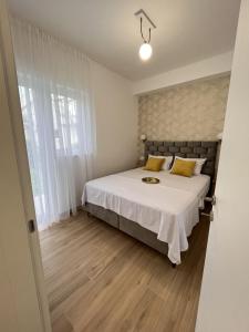 a bedroom with a bed with white sheets and yellow pillows at DMM Apartments in Tivat