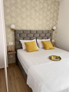 - une chambre avec un grand lit blanc et des oreillers jaunes dans l'établissement DMM Apartments, à Tivat