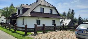 a white house with a wooden fence and a car at Chaluba Bully 243 in Donovaly