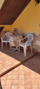 two white chairs and a bed in a room at Appartamento stile rustico in collina 