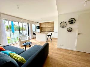 een woonkamer met een blauwe bank en een keuken bij Arradon Golfe du Morbihan Appartement 2 Pièces plain-pied Terrasse in Arradon