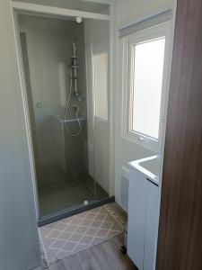 La salle de bains est pourvue d'une douche, d'un lavabo et d'un miroir. dans l'établissement mobil-home neuf 4-6 places camping Siblu les viviers, à Lège-Cap-Ferret
