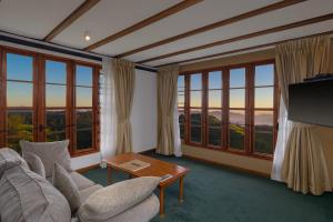 a living room with a couch and a table and windows at Heritance Tea Factory in Nuwara Eliya