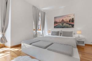 a white bedroom with a large bed and a painting on the wall at Charming apartment in the heart of Bratislava in Bratislava