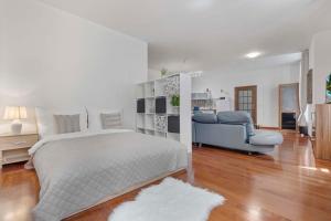 a white bedroom with a bed and a couch at Charming apartment in the heart of Bratislava in Bratislava