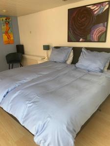 uma cama grande com lençóis brancos e almofadas em Duynsandt em Zandvoort
