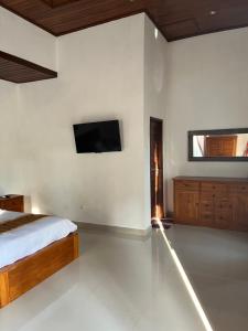 a bedroom with a bed and a tv on the wall at Villa Miracle Ubud in Ubud