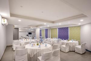 a banquet hall with white tables and white chairs at Inde Hotel Sec- 49, Golf Course Extension, Gurgaon in Gurgaon