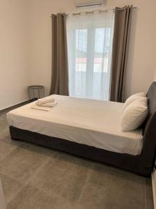 a large bed in a room with a window at Serenity - Brand new apartment in Ermioni Village in Ermioni
