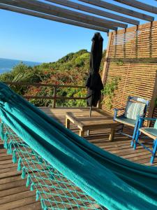 a hammock on a deck with a table and chairs at Pousada PARAÍSO 26 in Imbituba