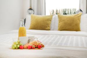 een ontbijt op een bed met een fles sinaasappelsap en fruit bij Camden and Kings Cross 3 bedroom flat - sleeps 8 in Londen