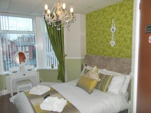 1 dormitorio con cama blanca y lámpara de araña en Delamere Hotel, en Blackpool