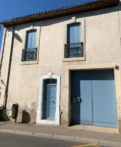 ein Gebäude mit zwei blauen Garagentüren auf einer Straße in der Unterkunft Appartement à 15min de la mer in Montblanc