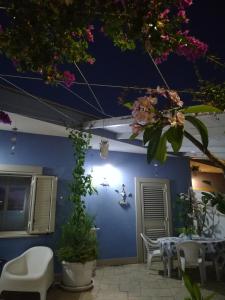 een patio met een tafel en stoelen en een blauwe muur bij "Villetta tra Mare e Barocco" in Marina di Ragusa