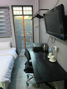 - une chambre avec un bureau, une télévision et un lit dans l'établissement Mekong Riverside, à Vientiane