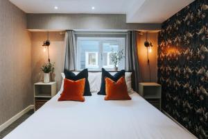 a bedroom with a large bed with orange and black pillows at 3 Bed Boutique Holiday Home in Town Centre in Tavistock