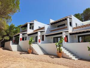 a white house with white steps and potted plants at Pinomar - Emar Hotels in Es Caló