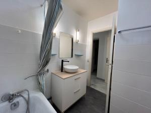 a white bathroom with a sink and a mirror at Appartement Cosy Montpellier in Montpellier