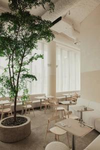 a tree in a room with tables and chairs at Enso District Hotel in Knokke-Heist