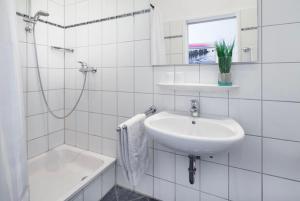 a white bathroom with a sink and a bath tub at Villa Rosenhof in Norderney +43 photos