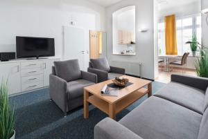 ein Wohnzimmer mit einem Sofa, Stühlen und einem Tisch in der Unterkunft Villa Rosenhof in Norderney