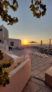 a sunset on the beach with benches and tables at Olympic Villas in Oia