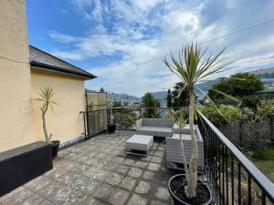 a balcony with a patio furniture and palm trees at Elim in Dartmouth with stunning River Dart view in Dartmouth