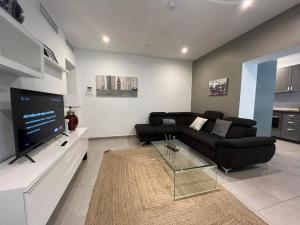 a living room with a black couch and a flat screen tv at 2BR 2BA with private patio your serene escape in Gibraltar