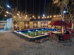 a swimming pool at night with a table and chairs at Urbanview Hotel Sakura Kampung Inggris Pare by RedDoorz in Pare