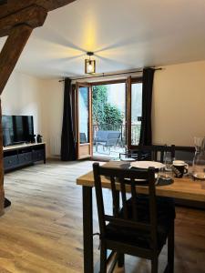 een woonkamer met een tafel en stoelen en een televisie bij Le Duplex in Auxerre