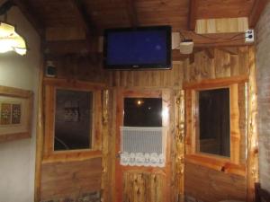 a television on the wall of a cabin with windows at Cabañas Valle Encantado Meliquina in Villa Meliquina