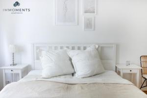 um quarto branco com uma cama com almofadas brancas em Stilvolles Apartment im Zentrum em Magdeburg