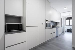 a white kitchen with white cabinets and a microwave at GuestReady - A prime stay near the beach in Matosinhos