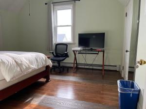 a bedroom with a bed and a desk with a television at Malden rooms in Malden