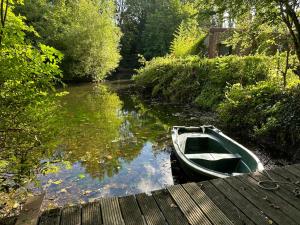 a boat sitting on a river next to a wooden dock at Le gîte du chastel in Frélinghien