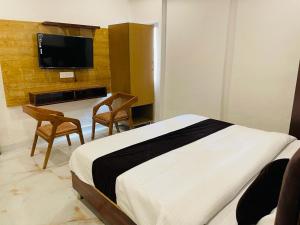 a bedroom with a bed and two chairs and a tv at Hotel Fusion in Kurukshetra