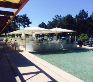 a pool with tables and umbrellas on top of it at Aroeira Golf in Charneca