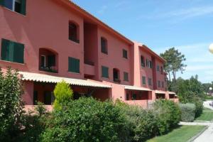 a large red building with green windows and bushes at Aroeira Golf in Charneca