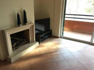 a living room with a fireplace and a window at Aroeira Golf in Charneca