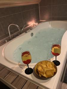 due bicchieri di vino e una ciotola di pane in una vasca da bagno di Antwerp West Side Attic a Zwijndrecht