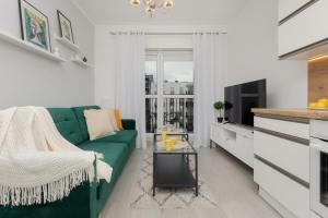een woonkamer met een groene bank en een tafel bij Cozy Apartment with Parking Bakalarska by Renters in Warschau