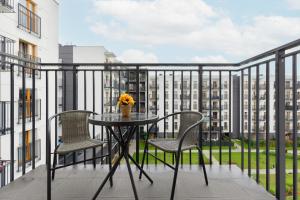 a table and chairs on a balcony with a building at Cozy Apartment with Parking Bakalarska by Renters in Warsaw