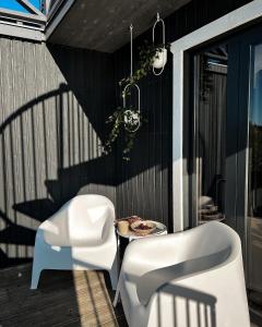 twee witte stoelen en een tafel op een patio bij Palikt niedrēs in Salacgrīva