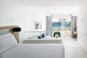 a white bedroom with a bed and a living room at Plus Fariones Suite Hotel in Puerto del Carmen