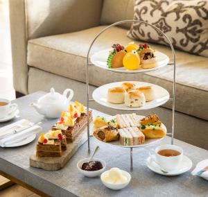 a table topped with plates of food and cups of tea at The Vineyard Hotel & Spa in Newbury