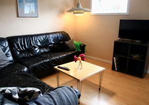 uma sala de estar com um sofá de couro preto e uma mesa de centro em Den gamle stald em Ovtrup