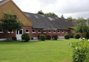 um grande edifício de tijolos vermelhos com relva em Den gamle stald em Ovtrup
