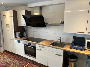 eine Küche mit weißen Schränken und einem Waschbecken in der Unterkunft Exclusiv Apartment Rödermark 3 Schlafzimmer in Rödermark