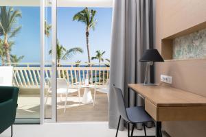 a room with a desk and a view of the ocean at Plus Fariones Suite Hotel in Puerto del Carmen
