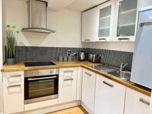 a kitchen with white cabinets and a sink at Forbury Apartment, 3 guests, Free Parking & Wifi, close to Uni, Hospital & Town Centre in Reading